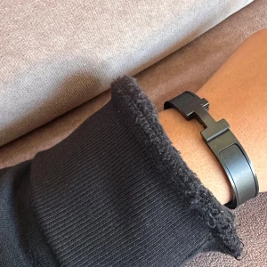 svart H armanmd - Stilrent svart armband med en unik geometrisk design. Perfekt för att ge en modern touch till din outfit. Armbandet har en enkel och elegant låsning.
