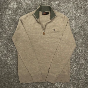 Beige ulltröja från Morris - Säljer en stilren beige halvzip från Morris i 100% merinoull. Tröjan har en dragkedja vid halsen med läderlapp och det ikoniska ”Morris” emblemet på bröstet. Det står storlek L men är mer som en XS-S eftersom den har krympt i tvätt. Vid eventuella funderingar så är det bara att höra av sig!