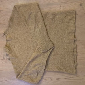 Beige stickad tröja - Mysig beige stickad tröja med långa ärmar och ribbade detaljer vid hals, ärmslut och nederkant. Perfekt för kyliga dagar. Storlek S