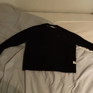 Svart tröja från Tommy Hilfiger - Säljer en stilren mörkblå tröja från Tommy Hilfiger. Tröjan har en liten logotyp på bröstet och en etikett vid nederkanten. Perfekt för en klassisk och avslappnad look.