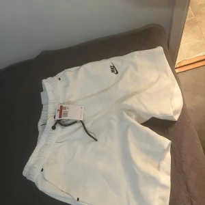 Vita shorts från Nike - Säljer ett par vita Nike shorts i nytt skick. De har en normal passform med snörning i midjan för justerbarhet. Perfekta för sommarens alla aktiviteter, oavsett om det är träning eller bara hänga med vänner. Materialet känns lätt och bekvämt. Köpt är köpt tar ej emot tbx 