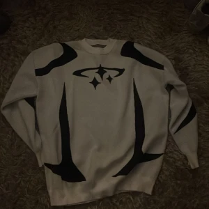 Vit och svart stickad tröja  - Snygg vit tröja med svart grafiskt mönster på framsidan och ärmarna. Otroligt skön och håller värmen utmärkt under vintern. Storlek M/L (båda funkar)