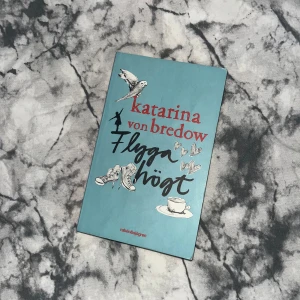 Flyga högt - Boken 'Flyga högt' av Katarina von Bredow handlar om Vendela som är femton och precis börjat nian. Det är en berättelse om att hitta sin plats i skolan och att våga vara sig själv. Omslaget är turkost med illustrationer av en fågel, högklackade skor och en tekopp, vilket ger en känsla av frihet och ungdom. Pocketformat. Pris går att diskuteras☺️