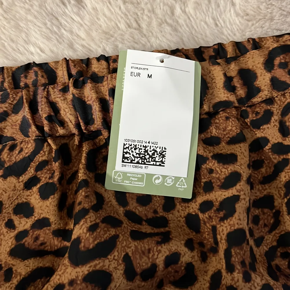 Säljer en supercool leopardmönstrad kjol i brunt och svart. Kjolen är i ett mjukt och glansigt material, perfekt för att sticka ut på festen eller bara för en vardagslook med attityd. Den har en elastisk midja för extra komfort. Passar perfekt till både sneakers och klackar! Men slits på båda sidorna.. Hameet.
