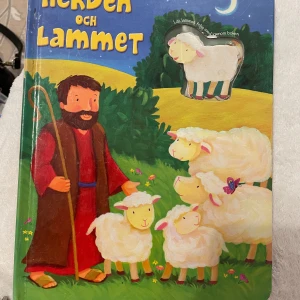 Herden och Lammet - En interaktiv barnbok om den gode herdens omsorg och kärlek. Boken har färgglada illustrationer och flikar som barnen kan lyfta för att upptäcka vad som händer på nästa sida. Passar för barn i åldern 3-5 år.