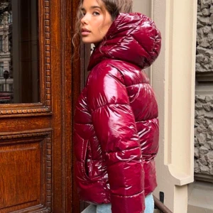 Vinröd glansig pufferjacka Nelly Everyday shiny puffer jacket - Populär puffer från Nelly. Helt slutsåld. Storlek XS. Snygg vinröd pufferjacka med glansig finish och stor huva. Perfekt för kyliga dagar med sin vadderade design. Jackan har en modern look och är ett måste för garderoben. Använd en gång. 