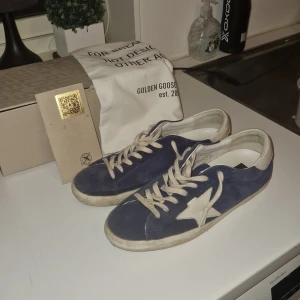 Blå sneakers från Golden Goose - Säljer ett par snygga blå sneakers från Golden Goose i bra skick. Skorna är i mocka och har en vintage-look med en vit sula. Perfekta för en avslappnad stil! Priset börjar på 2600 men är öppen för bud!               OBS! ljuset gör så att skorna ser smutsigare ut än vad dom är det är bara att fråga för mer bilder