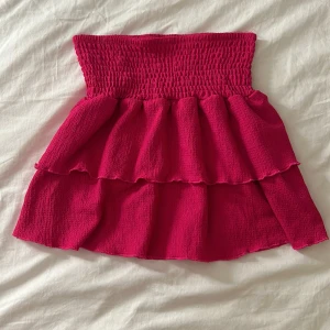 Rosa kjol från Gina Tricot - Säljer en superfin rosa kjol från Gina Tricot i storlek 146/152. Kjolen har en smockad midja och volanger.💘