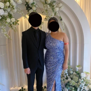 Glittrig blå klänning med slits - En elegant, glittrig blå klänning med en axel och slits. Perfekt för festliga tillfällen. Endast använd ett par timmar,priset går att diskutera!