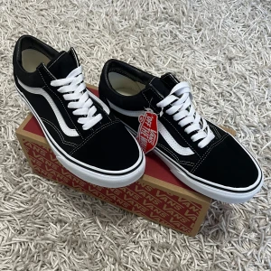 Vans skor - Säljer ett par klassiska Vans Old Skool sneakers i svart och vitt. De har en snygg design med vit sula och ikoniska sidostripes. Skorna är i nytt skick och kommer i originalkartong. Perfekta för både vardag och fest!