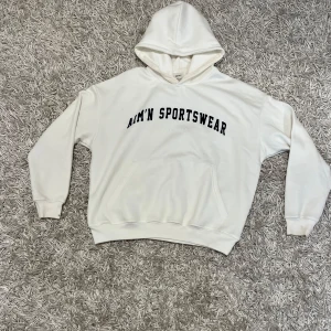 Aim'n Sportswear hoodie - Säljer en supermjuk och bekväm vit hoodie från Aim'n. Perfekt för mysiga dagar eller träning. Den har en klassisk design med Aim'n Sportswear-tryck på framsidan. Hoodien är i storlek L och har en rymlig passform. Perfekt för höst och vinter!