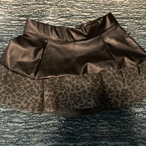 Lågmidjad mini skirt - Super snygg lågmidjad kort kjol i svart läder med leopardvolang, perfekt för fest! 🐆✨säljer den då den var för lite för mig, kom privat om ni vill ha fler bilder. Tror den är i strlk xs men kan passa S om man har smalare höftet