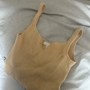 Gul ribbad linnetopp - Säljer en superfin gul ribbad linnetopp i mycket bra skick. Toppen har en v-ringad design och är perfekt för sommardagar. Den är ärmlös och har en skön passform som passar till både vardag och fest. Perfekt att matcha med jeans eller kjol!