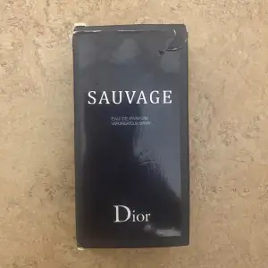 Säljer en flaska Sauvage Eau de Parfum från Dior, 100 ml. Flaskan har en elegant design med en mörk tonad glasflaska och svart lock. Perfekt för den som söker en sofistikerad och maskulin doft.