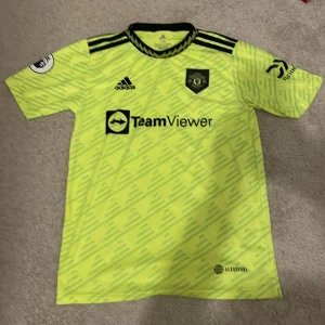 Gul Manchester United fotbollströja - Säljer en grymt snygg gul Manchester United fotbollströja från Adidas. Den har korta ärmar och ett coolt mönster med klubbens emblem på bröstet. Perfekt för alla United-fans! 🟡⚽