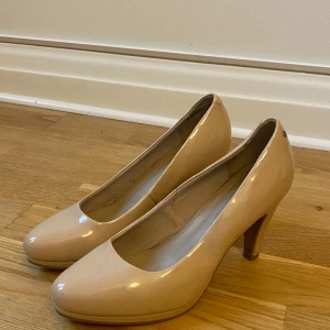 Beige pumps med klack - Säljer ett par eleganta beige pumps i mycket bra skick. De har en klassisk design med rundad tå och en stabil klack som ger bra höjd. Perfekta för både fest och mer formella tillfällen. Skorna är bekväma och stilrena, vilket gör dem lätta att matcha med olika outfits.
