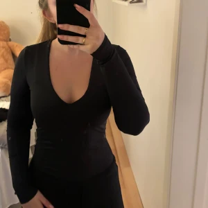 Svart långärmad body - svart långärmad body med djup v-ringning. Den har en tight passform som framhäver figuren🖤