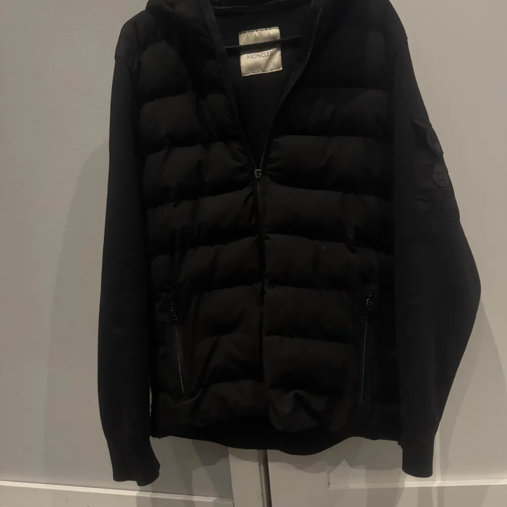 Säljer en snygg svart dunjacka från Moncler i mycket bra skick. Jackan har en dragkedja framtill och långa ärmar. Perfekt för höst och vinter med sin quiltade design som håller dig varm. Den har en stilren look med en liten ficka på ärmen.. Jackor.