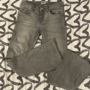 Grå jeans från 157 - Säljer ett par grå jeans från 157 i storlek XS. De har en low bootcut-stil och är i kort längd. Perfekta för en avslappnad look och passar bra till både vardag och fest. De är i bra skick och redo för en ny ägare!