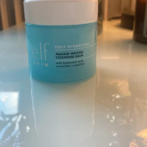 e.l.f. Holy Hydration! Makeup Melting Cleansing Balm - En återfuktande rengöringsbalm från e.l.f. som smälter bort smink effektivt. Innehåller hyaluronsyra, ceramider och peptider för att vårda huden. Passar torr, oljig och kombinerad hud. Perfekt för daglig användning för att rengöra och återfukta huden. Den är knappt använd och köptes för nån månad sen i usa