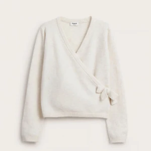 Vit omlott tröja från kappahl - Superfin vit omlott tröja från kappahl i mjukt material. Den har en v-ringad design med knytning på sidan och långa ärmar. Perfekt för både vardag och festliga tillfällen. Passar bra till jeans eller kjol för en stilren look!