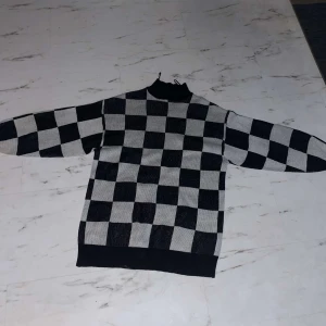 Svart och vit rutig tröja - Säljer en cool svart och vit rutig tröja med långärmad design. Perfekt för att hålla sig varm och stilren under höst och vinter. Tröjan har en normal passform och är gjord i ett mjukt material som känns skönt mot huden.