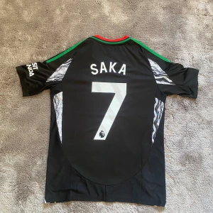 Arsenal tröja 24/25 borta - Saka 7 - Säljer denna Arsenal tröja med Saka på ryggen. Storleken är S men passar även M.