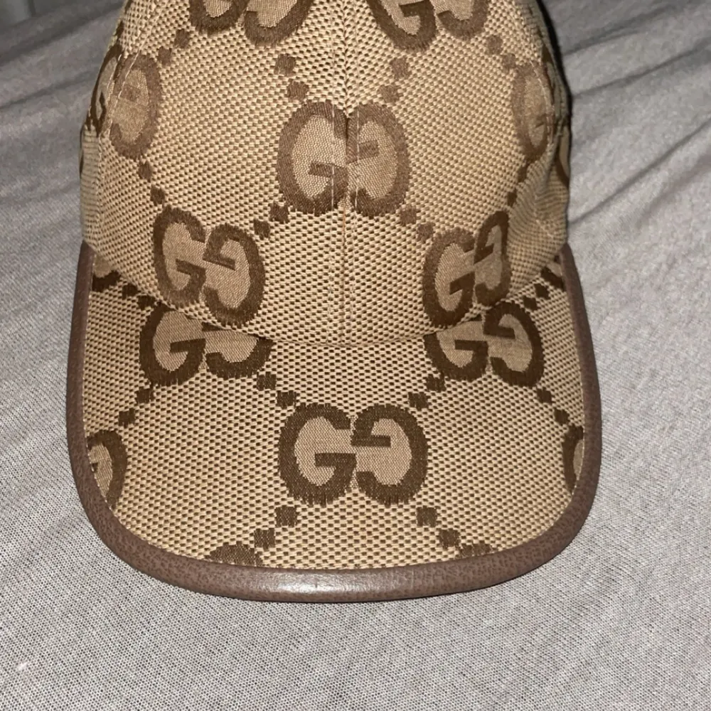 Säljer en snygg beige keps Gucci Jumbo från Gucci med GG-mönstret i brunt. Kepsen har en justerbar rem baktill för perfekt passform. Kepsen är i nyskick och är perfekt.. Accessoarer.