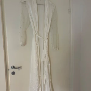 Vit brudrock med pärlor  - Vit brudrock med pärlor på armarna. Fint satintyg och knytbar. 