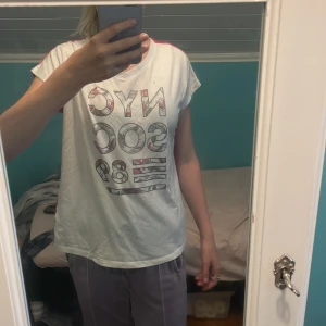 En rosa/vit t-shirt - En rosa/vit t-shirt med text på fram sidan.