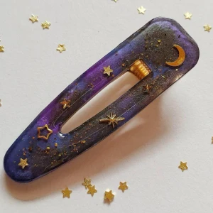 Hårklämma med stjärnor och måne - Handgjord galaxhårklämma. Första bilden är lånad från Etsy-shoppen där klämman köptes ifrån. Klämman är mer av en hårdekoration än en klämma som kan fästa håret på plats. Ord. pris 170kr. Knappt använd. ***Köpare står för frakt om inget annat anges!