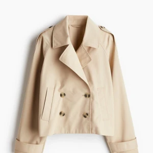 Kort trenchcoat - Kort trenchcoat ifrån hm Aldrig använd men lapparna av. Ganska oversized så passar M också! Slut i storlek S hos Hm!