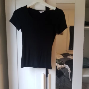 Svart ribbad topp - Säljer en snygg svart ribbad topp med korta ärmar. Perfekt för både vardag och fest. Toppen har en tight passform och är superbekväm att bära.