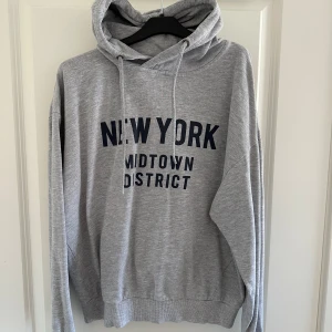 Grå hoodie från 157 - Säljer en grå hoodie från 157 med en klassisk känguruficka och justerbar huva med snören. Passar perfekt till höst och vår! 