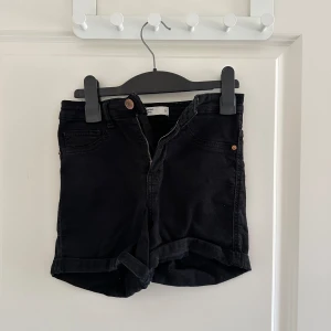 Svarta jeansshorts från G Perfect Jeans - Säljer ett par snygga svarta jeansshorts från Gina Tricot Perfect Jeans. De är högmidjade med en klassisk femficksdesign och har en dragkedja framtill. Perfekta för sommaren och kan enkelt matchas med en t-shirt eller blus för en avslappnad look. Finns även i blått och vitt i min profil!💘