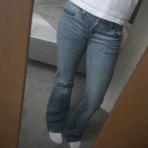 Blå low waist jeans   - Säljer dessa jeansen från h&m med knappar på bakfickorna eftersom dom inte kommer till användning. Passar perfekt i längden för mig som är 163 cm lång. Jeansen har inga defekter och är i bra skick, ser ut som nya och endast använda 2-3 gånger.
