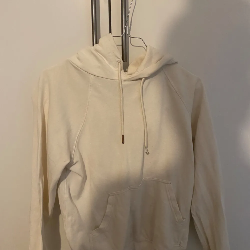 Säljer en  bekväm beige hoodie. Den har en klassisk design med en stor ficka fram och justerbar dragsko i huvan. Perfekt för mysiga dagar eller som ett lager under jackan. Passar till allt och är ett måste i garderoben!. Hoodies.