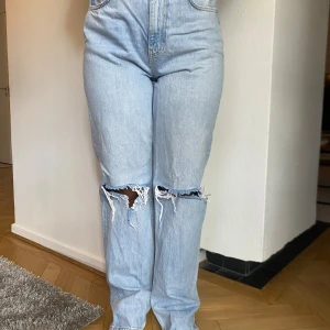Ljusa jeans med slitningar - Säljer ett par ljusa jeans från Gina tricot  i storlek 36. De har en hög midja och är i straight modell. Jeansen har coola slitningar vid knäna som ger en avslappnad look. Perfekta för både vardag och fest!