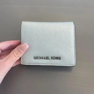 Michael kors plånbok - Säljer nu min fina silvriga Michael kors plånbok. Inköpt på nk i Sthlm för några år sedan! Måtten är 11cm lång och 9cm hög, passar alltså perfekt i både mindre och större väskor. Fint skick! Pris kan diskuteras.