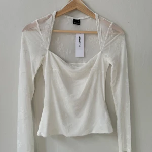 Vit blommig topp från Gina Tricot - Säljer en superfin vit topp från Gina Tricot i storlek XS. Den har ett blommigt mönster och är gjord i ett tunt, genomskinligt material upptill. Toppen har långa ärmar och en fyrkantig halsringning. Perfekt för både vardag och fest!