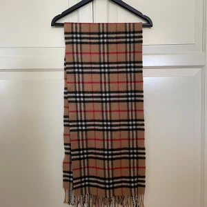 Burberry halsduk - Mycket bra skick, använd fåtal gånger, den har varit med ett tag så kvitto och rubbet saknas. Det går att pruta.