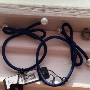 Mörkblå hårband med pärlor - Säljer två supergulliga mörkblå hårband med stora pärlor. De har en söt rosettform och är perfekta för att piffa upp vilken outfit som helst. Passar både till vardag och fest!