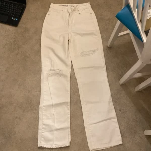 Vita jeansbyxor från Never Denim - Säljer ett par vita jeansbyxor från Never Denim i storlek 26/32. Byxorna har en avslappnad wide fit och är högmidjade. De har snygga slitningar på benen som ger en cool look. Perfekta för både vardag och fest! 🕺