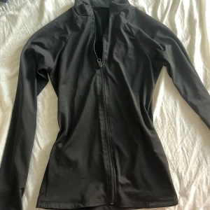 Svart långärmad tröja med dragkedja - Säljer en svart långärmad träningströja med dragkedja framtill och fickor!  Perfekt för både träning och vardag. Tröjan har en tight passform och är gjord i ett mjukt och stretchigt material. Passar bra till höst och vår. Storlek s och är från Shein! Hör av dig vid intresse!