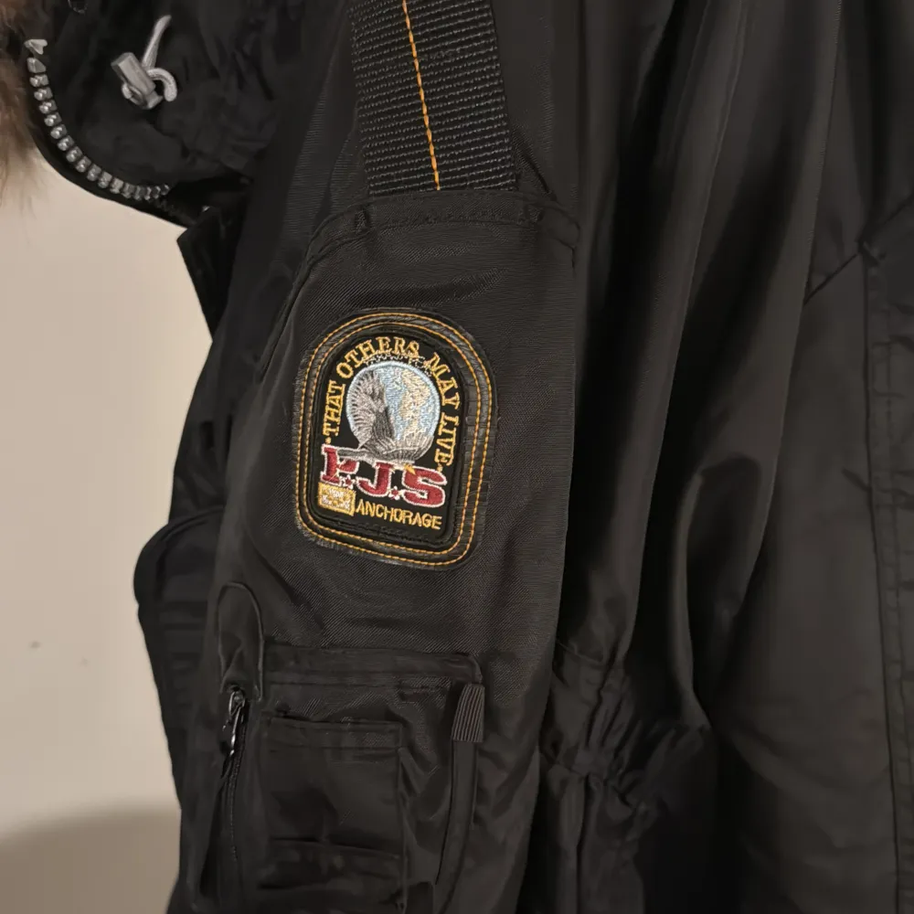 Säljer en svart Parajumpers vinterjacka i storlek XXL. Den har en snygg pälsfodrad huva och flera praktiska fickor. Jackan är i mycket bra skick och perfekt för kalla vinterdagar. Den har en dragkedja och knappar för extra skydd mot kyla. Broderad patch på ärmen ger en cool detalj. Jag använder den inte för den är för stor för mig. Pris kan diskuteras . Takit.