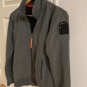 Grå jacka från Parajumpers - Säljer en snygg grå jacka från Parajumpers i mycket bra skick. Den har en dragkedja framtill och en cool detalj på ärmen. Perfekt för höst och vår, och den är långärmad för extra värme. Passar bra till både vardag och lite mer avslappnade tillfällen.