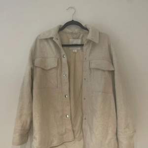 Säljer en snygg beige overshirt från Monki i storlek XS. Den har en avslappnad passform med långa ärmar och knappar framtill. Perfekt för lager-på-lager under hösten eller våren. Två stora bröstfickor ger en cool look. 🧥✨