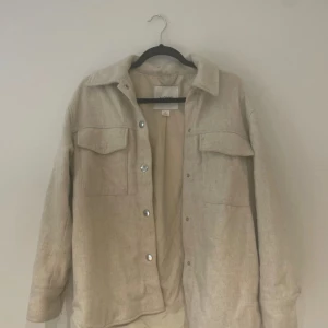 Beige overshirt från Monki - Säljer en snygg beige overshirt från Monki i storlek XS. Den har en avslappnad passform med långa ärmar och knappar framtill. Perfekt för lager-på-lager under hösten eller våren. Två stora bröstfickor ger en cool look. 🧥✨