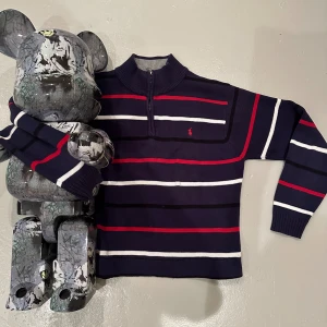Ralph Lauren stickad tröja - En skön ralph lauren tröja för vintern, nästan i nyskick! En fet design med randigt rött och vitt, har en liten defekt vid sömmen men inget som märks av! IN OCH KÖP!