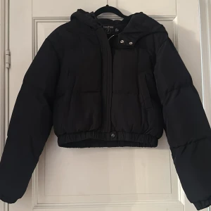 Svart pufferjacka från Boohoo - Säljer en svart pufferjacka från Boohoo i storlek  XS. Jackan har en mysig huva och dragkedja framtill. Perfekt för kyliga höst- och vinterdagar. Den är i mycket bra skick och redo för nya äventyr! 🖤